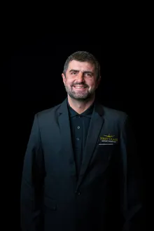 Smiling First Class Airport Transport chauffeur with a beard, in the company black blazer