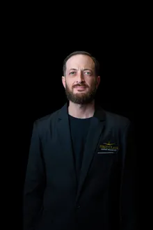 Bearded First Class Airport Transport chauffeur in the company black blazer